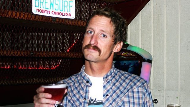 Jeff Myers and his beautiful moustache holding a beer at the Outer Banks Brewing Station
